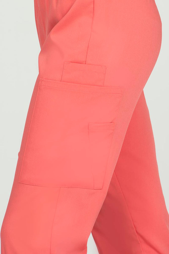 A young female Sonographer wearing an Epic by MedWorks Women's Elastic Waist Scrub Pant in Coral size medium featuring one outside pen pocket.