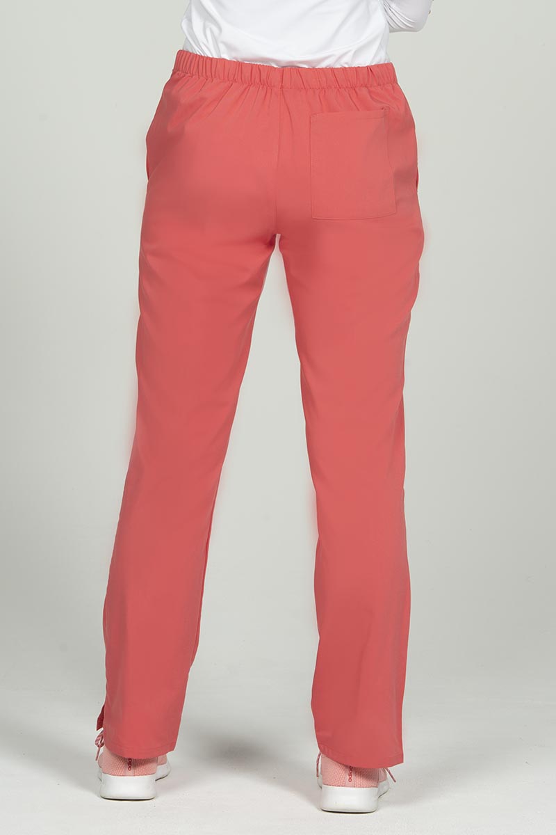 A female RN wearing an Epic by MedWorks Women's Natural Rise Flare Leg Scrub Pant in Coral size 2XL featuring 1 back patch pocket. 