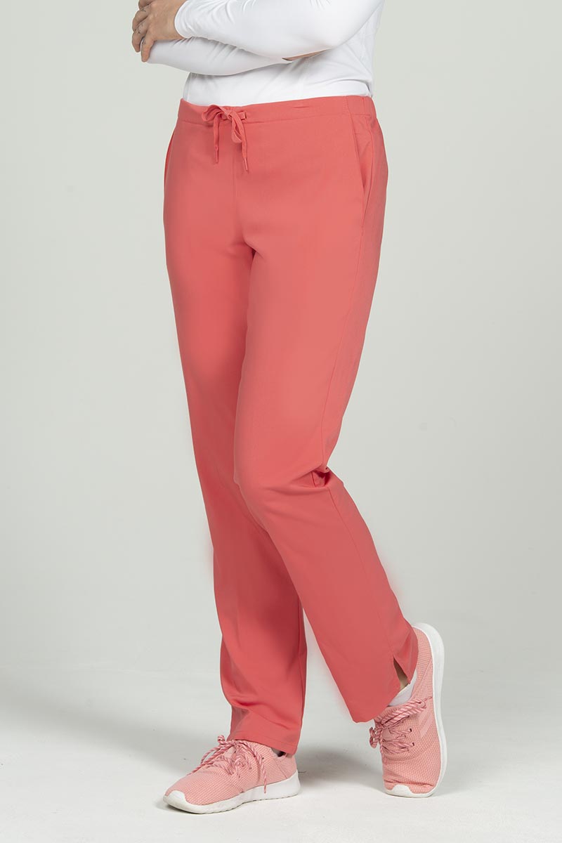 A young female Pharmacy Technician wearing an Epic by MedWorks Natural Rise Flare Leg Scrub Pant in Coral size small featuring a unique stretch fabric made of 77% Polyester, 21% Viscose, 2% Spandex.