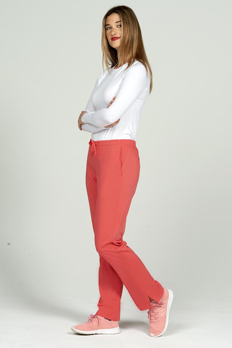 A full body image of a female Clinical Laboratory Technologist wearing an Epic by MedWorks Women's Natural Rise Flare Leg Scrub Pant in Coral size 3XL featuring a total of 3 pockets.