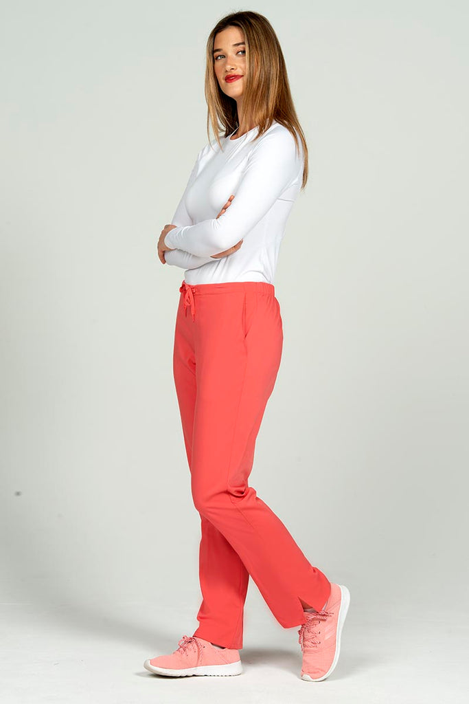 A full body image of a female Clinical Laboratory Technologist wearing an Epic by MedWorks Women's Natural Rise Flare Leg Scrub Pant in Coral size 3XL featuring a total of 3 pockets.