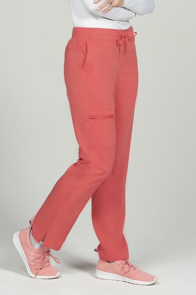 A female Nurse Practitioner wearing an Epic by MedWorks Women's Skinny Yoga Scrub Pant in Coral size XS featuring side slits.