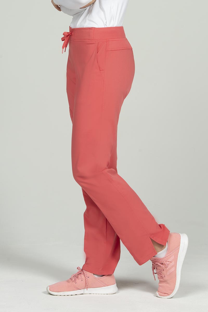 A young female Veterinary Technologist wearing an Epic by MedWorks Women's Skinny Yoga Scrub Pant in Coral size 3xl featuring 2 front slash pockets.