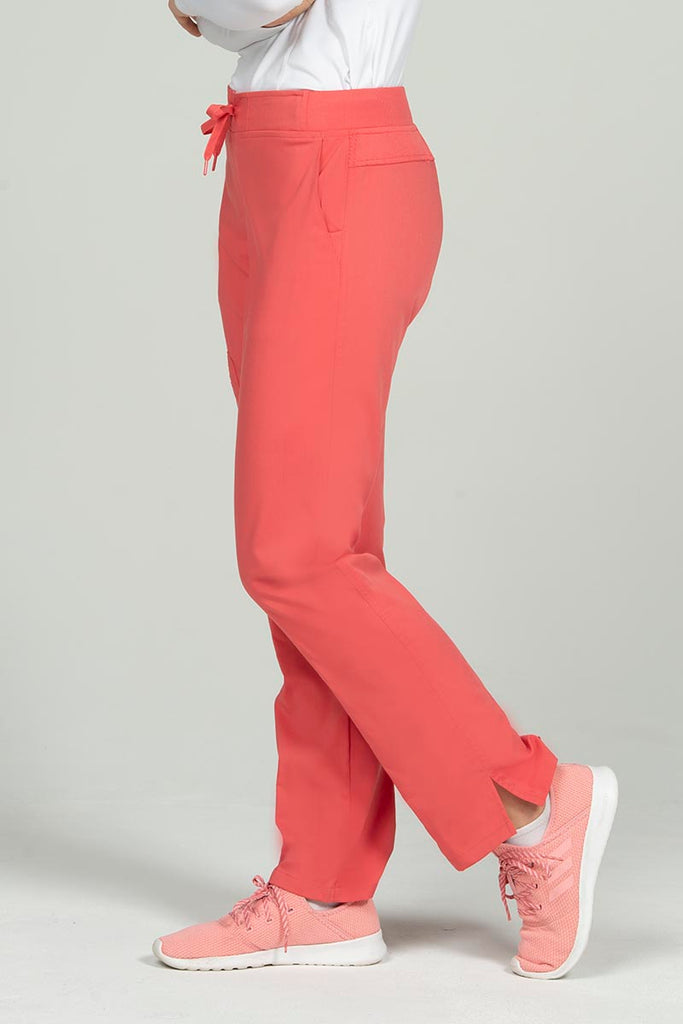 A young female Veterinary Technologist wearing an Epic by MedWorks Women's Skinny Yoga Scrub Pant in Coral size 3xl featuring 2 front slash pockets.