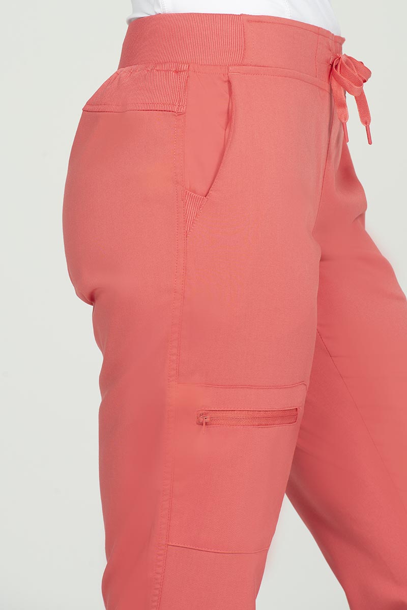 A young female Nurse Anesthetist wearing nan Epic by MedWorks Women's Skinny Yoga Scrub Pant in Coral size Medium Petite featuring a total of 3 pockets.