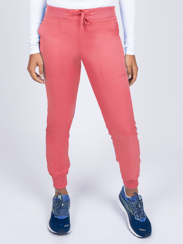 A young female Phlebotomist wearing an Epic by MedWorks Women's Yoga Jogger Scrub Pant in Coral size 3XL featuring a contemporary fit.