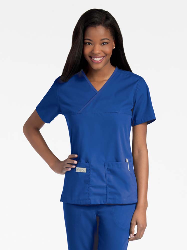 Young lady wearing an Urbane Essentials Women's Crossover Scrub Top in "Galaxy Blue" featuring a unique crossover neckline for a flattering fit.