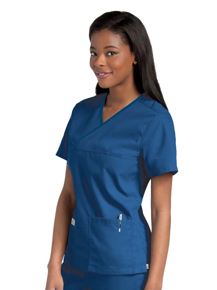 Female nurse wearing an Urbane Essentials Women's Crossover Scrub Top in "Galaxy Blue" featuring 2 front patch pockets.