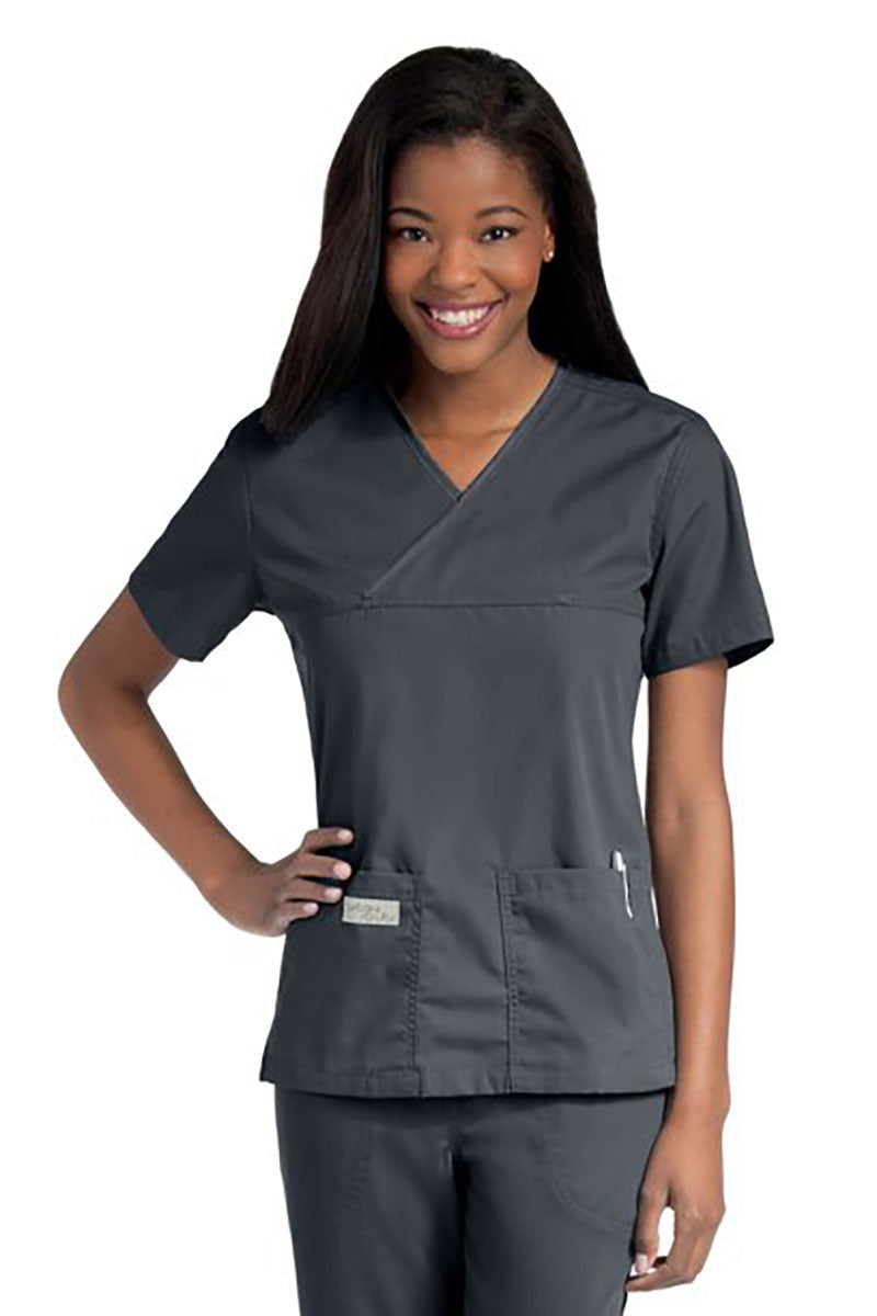 Young lady wearing an Urbane Essentials Women's Crossover Scrub Top in "Steel Grey" featuring a unique crossover neckline for a flattering fit.