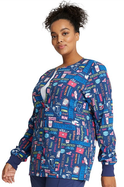 A young Home Care Registered Nurse wearing a Cherokee Women's Print Snap Front Jacket in "Scrub Life" featuring front princess seaming for a flattering fit.