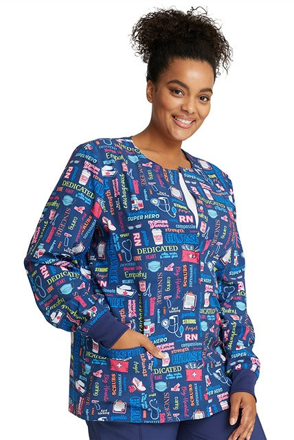A young LPN wearing Cherokee Women's Print Snap Front Jacket in "Scrub Life" featuring 2 front patch pockets.