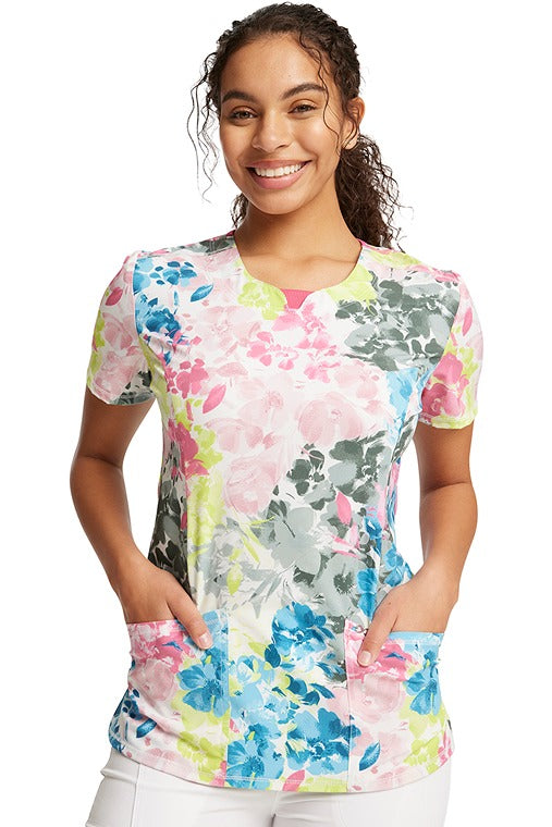 A young female nurse wearing a Women's Round Neck Print Top from Cherokee Infinity in "Brush Away Blooms" featuring a round neckline.