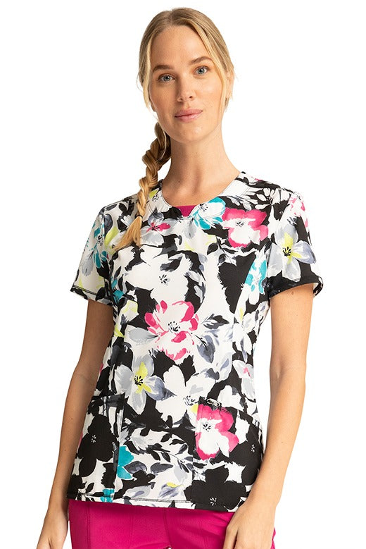 A young female CNA wearing a Women's Round Neck Print Top from Cherokee Infinity in "Inky Garden".