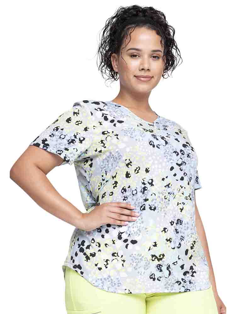 Young nurse wearing a Women's V-Neck Print Scrub Top from Cherokee in "Spots Go" featuring 2 front angled welt pockets.