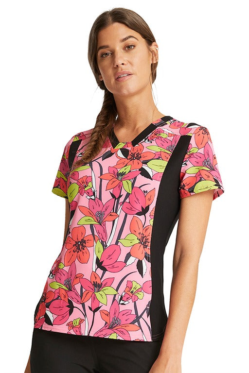 A young female CNA wearing a V-Neck Knit Panel Print Scrub Top from Cherokee iFlex in "Retro Blooms".
