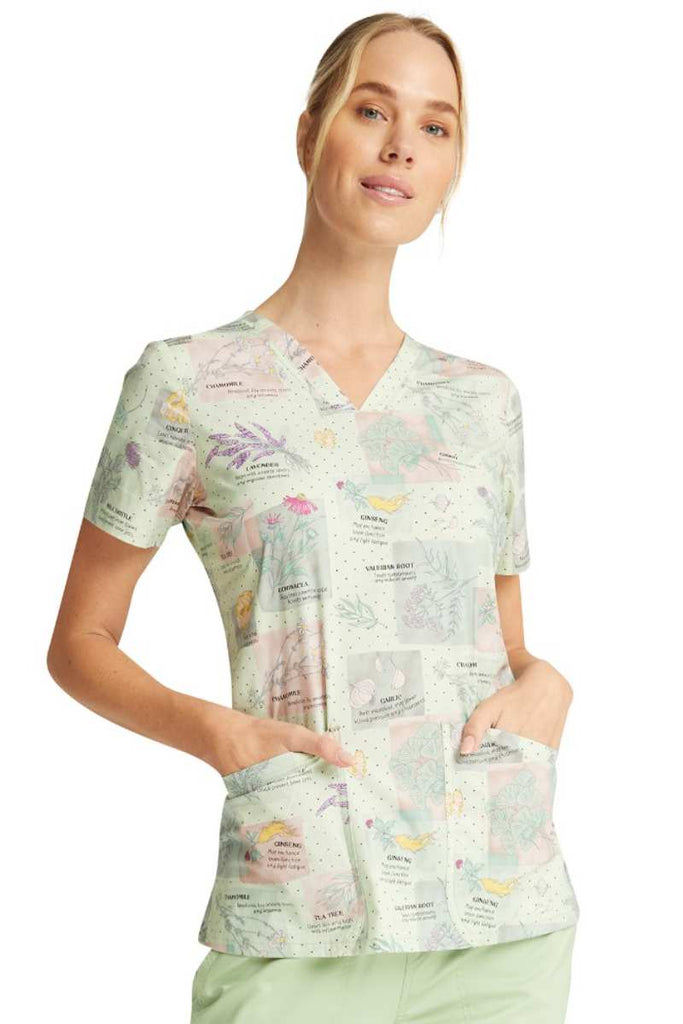 A young female Dental Hygienist wearing a Cherokee Women's V-neck Print Scrub Top in "Herbal Wellness" featuring a breathable cotton blend and flattering fit.