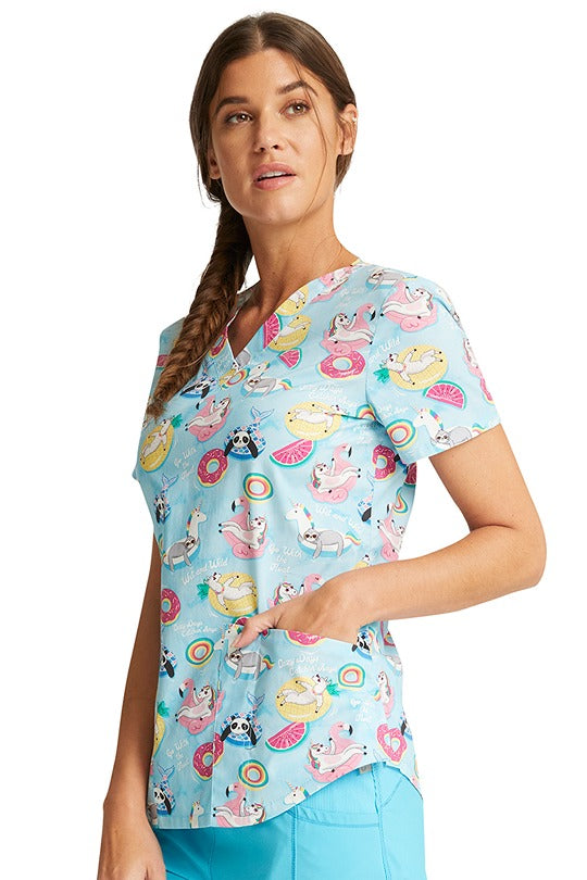 A female LPN wearing a Cherokee Women's V-Neck Print Scrub Top in" Go With The Float" featuring 2 front patch pockets & an additional pen slot. 