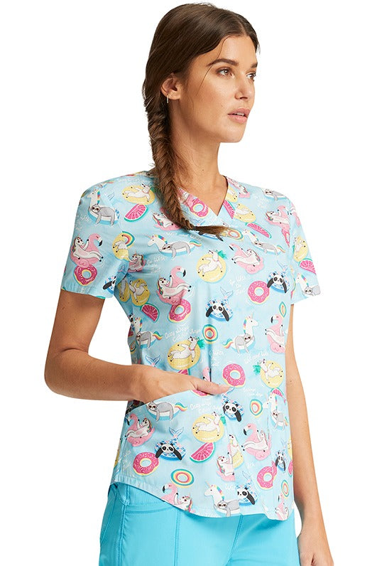 A female CNA wearing a Cherokee Women's V-Neck Print Scrub Top in "Go With The Float" featuring side vents for additional range of motion.