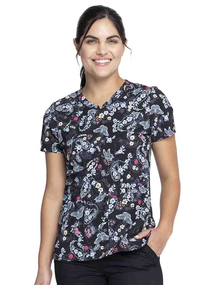 Young woman wearing a Cherokee Women's V-Neck Print Top in "Flutter Blooms" featuring a straight hemline.