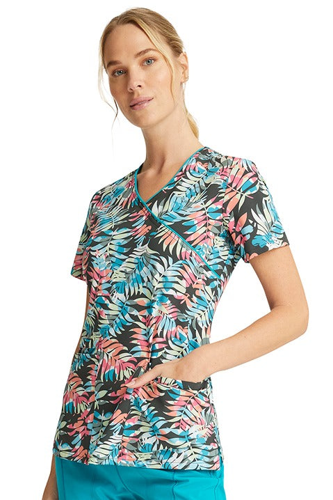 A young CNA wearing a Cherokee Women's Mock Wrap Print Top  in "Loving Tropic" featuring mock wrap y-neckline.