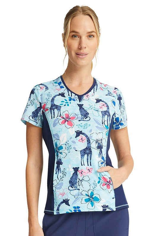 A young female Nurse wearing a Cherokee Women's V-neck Print Scrub Top in "Jungle Blues" size Large featuring short sleeves.