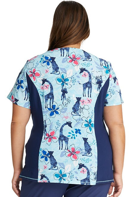 A young female Physician wearing a Cherokee Women's V-neck Print Scrub Top in "Jungle Blues" size Large featuring short sleeves & a rib knit inset at the neck for additional comfort throughout the day.