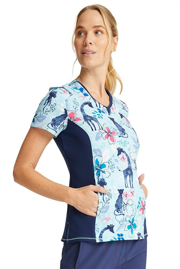 A young female Physical Therapy Assistant wearing a Cherokee Women's V-neck Print Scrub Top in "Jungle Blues" featuring a kangaroo pocket.