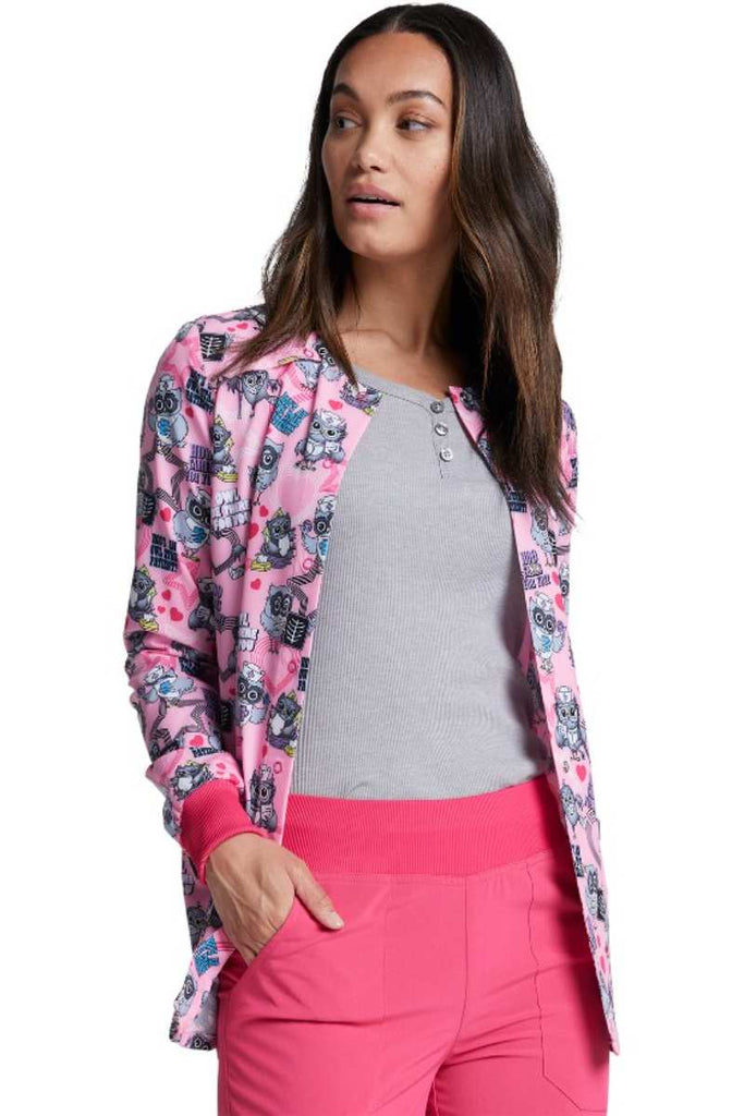 A young female CNA wearing a Dickies Dynamix Women's Snap Front Warm-Up Jacket in "Hoo Cares for You" featuring knit cuffs for a polished look.