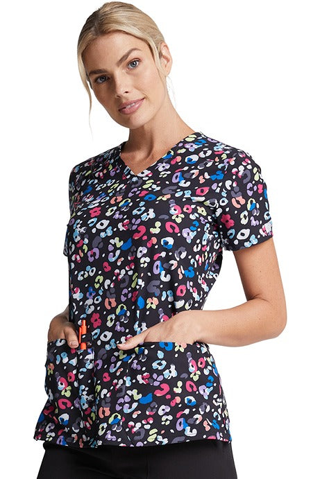 A female LPN wearing a Dickies Women's V-Neck Print Scrub Top in "Safari Pop" featuring 2 front patch pockets.