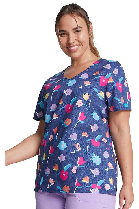 A young female LPN wearing a Dickies Women's V-Neck Print Scrub Top in "Denim Garden" featuring a relaxed v-neckline.