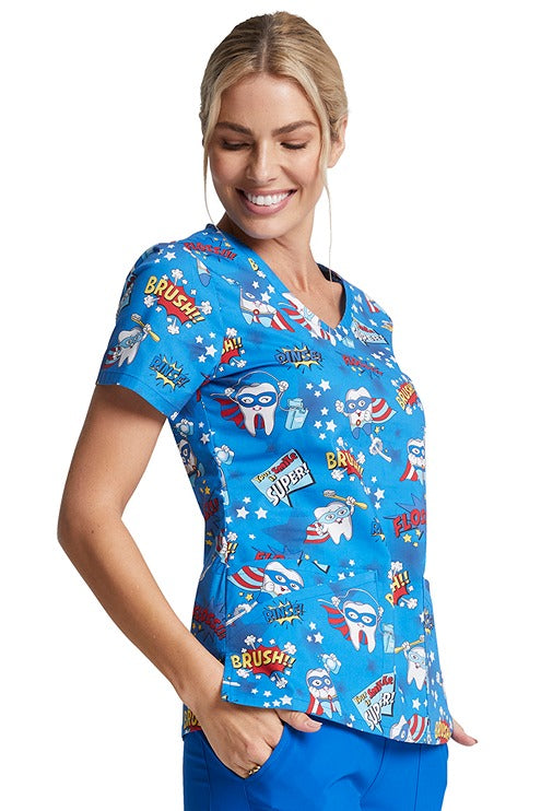 A female nurse wearing a Dickies Women's V-Neck Print Top in "Super Smile" featuring side vents for ease of movement.