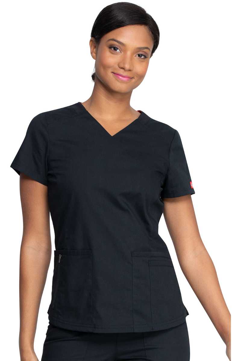 A young female Medical Assistant wearing a Dickies Women's V-Neck Scrub Top in Black size Medium featuring a total of 4 pockets.