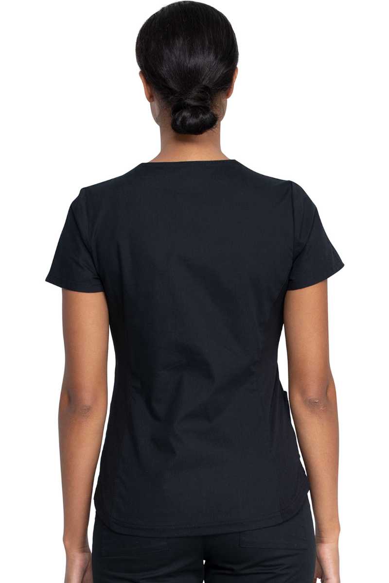 A young female Physician wearing a Dickies EDS Signature Women's V-neck Scrub Top in Black size XL featuring rib knit back side panels for additional range of motion.