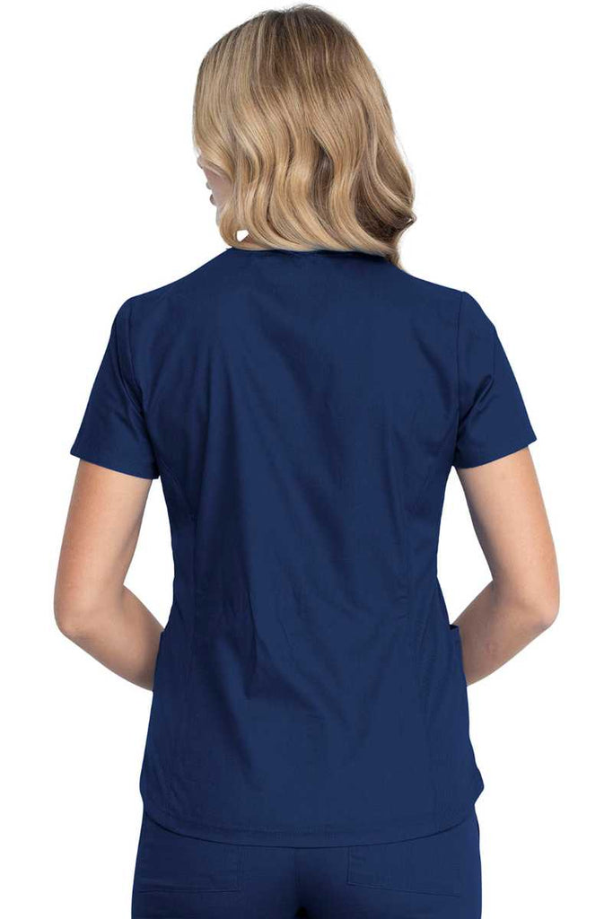 A young female Physician wearing a Dickies EDS Signature Women's V-neck Scrub Top in Navy size XL featuring rib knit back side panels for additional range of motion.