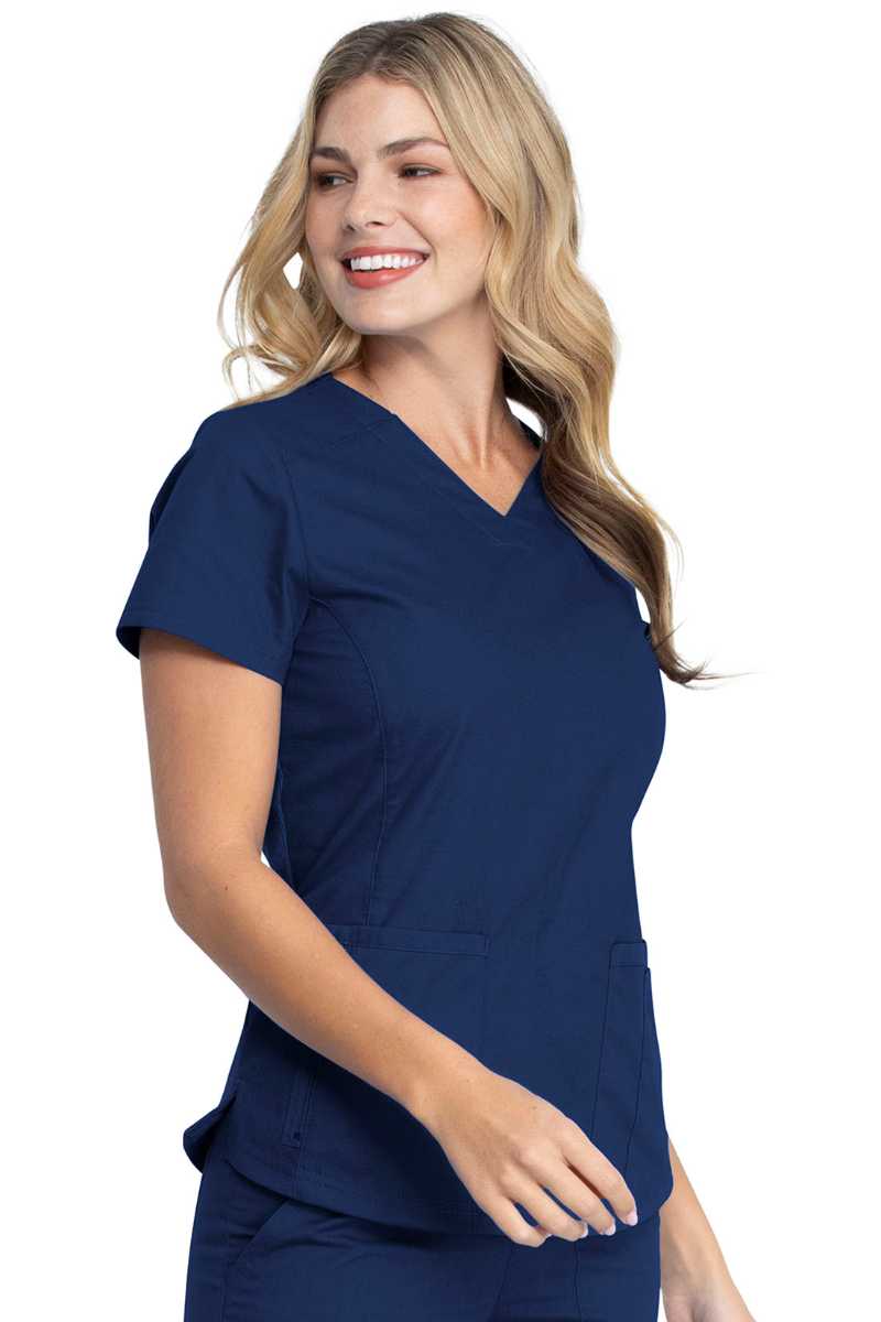A young female LPN wearing a Dickies EDS Signature Women's V-neck Scrub Top in Navy size 2XL featuring princess seaming throughout the front.