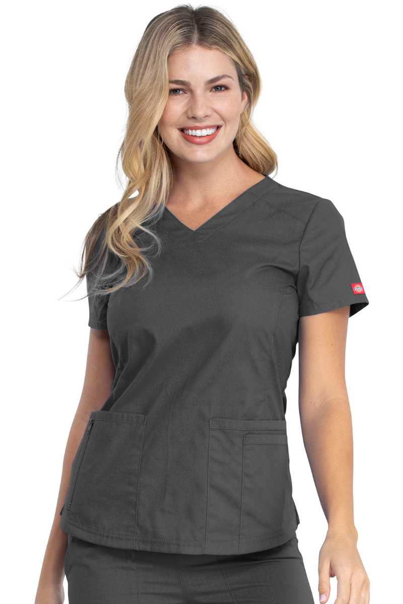A young female Medical Assistant wearing a Dickies Women's V-Neck Scrub Top in Pewter size Medium featuring a total of 4 pockets.