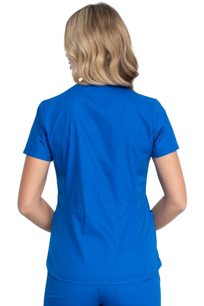 A young female Physician wearing a Dickies EDS Signature Women's V-neck Scrub Top in Royal size XL featuring rib knit back side panels for additional range of motion.