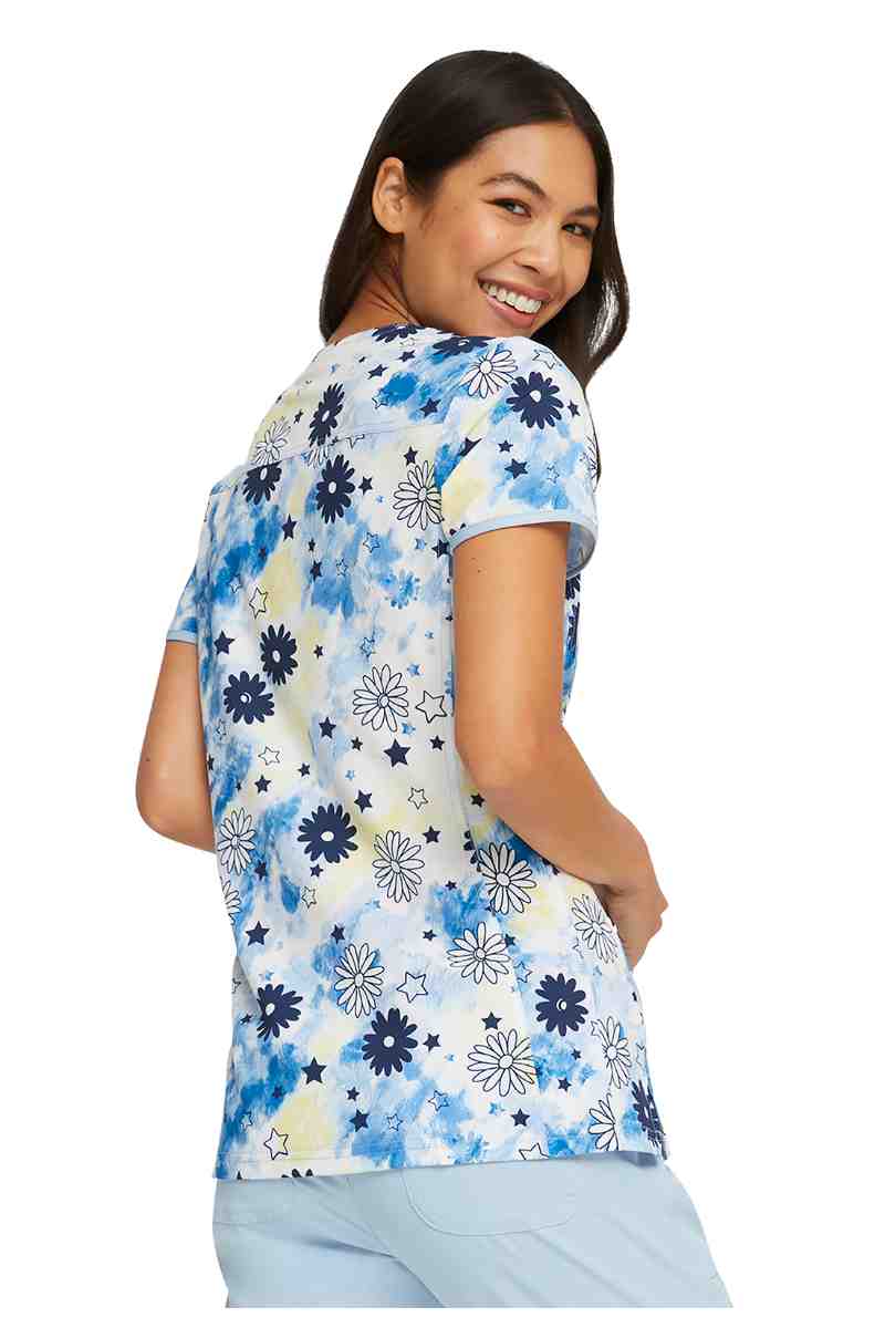 A young female Nursing Student wearing a HeartSoul Women's V-neck Print Scrub Top in "Daisy Spirit" size XS featuring a back yoke & side vents.