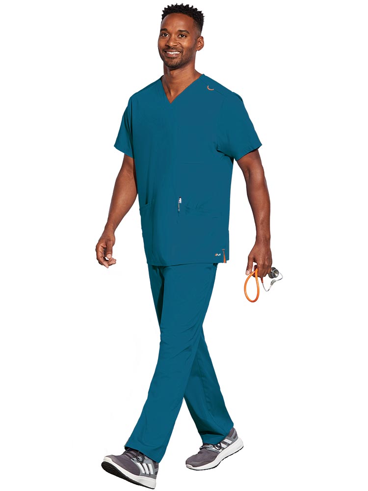 Young male LPN wearing a Unisex V-Neck Scrub Top from Barco Motion in Bahama size Large featuring a total of 5 pockets for all of your daily storage needs.