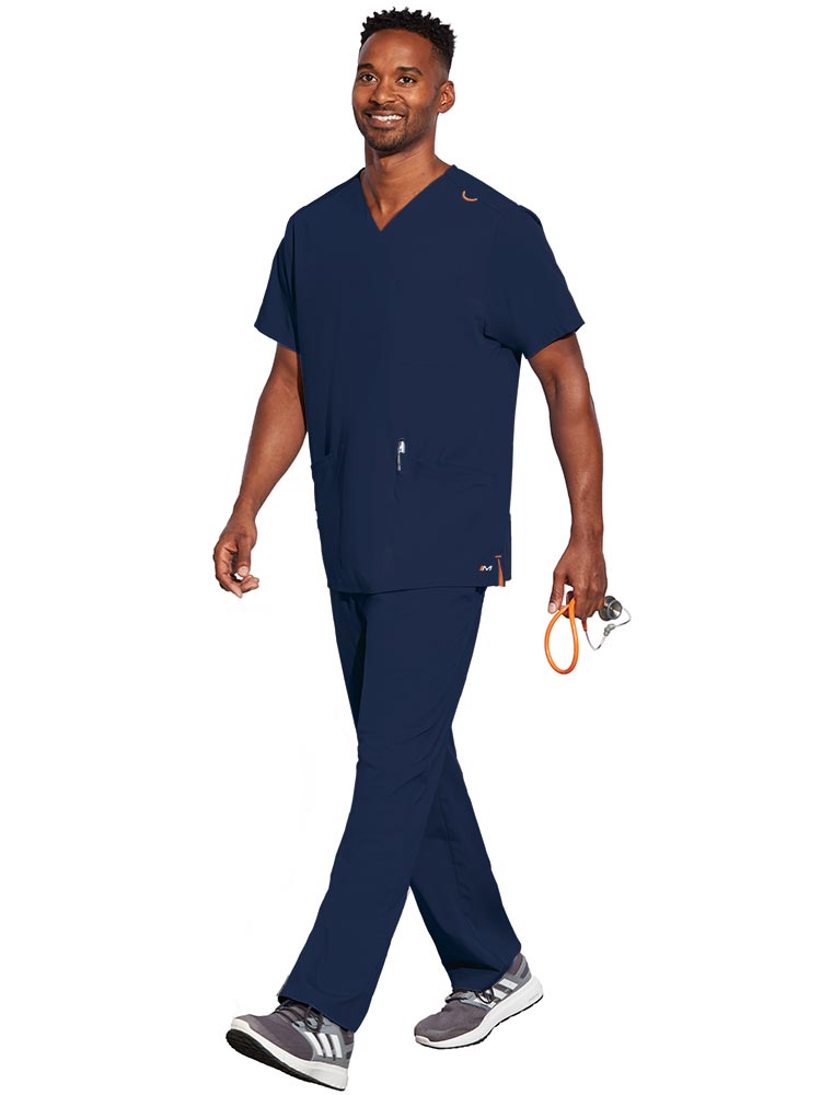 Young male LPN wearing a Unisex V-Neck Scrub Top from Barco Motion in Navy size Medium featuring a total of 5 pockets for all of your daily storage needs.