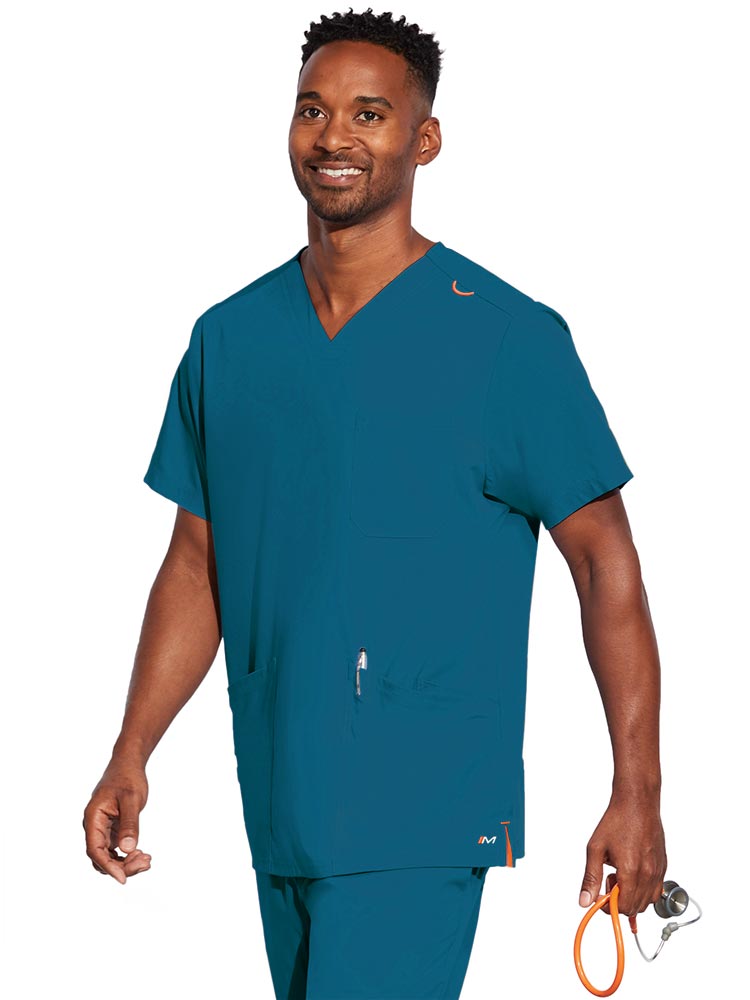 A young male CNA wearing a Barco Motion Unisex V-Neck Scrub Top in Bahama size Small featuring a V-neckline with lap over styling.