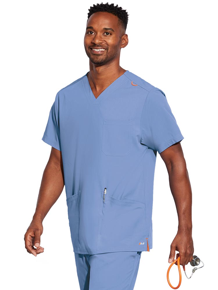 A young male CNA wearing a Barco Motion Unisex V-Neck Scrub Top in Ceil size 2XL featuring a V-neckline with lap over styling.