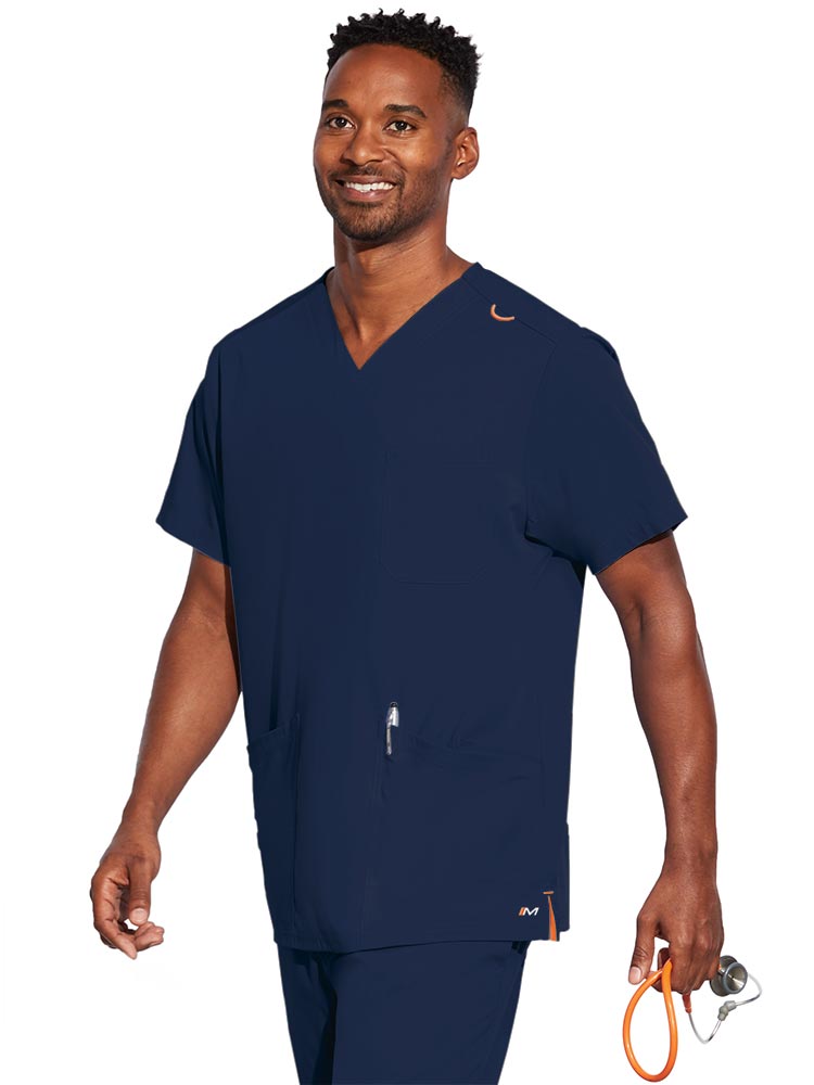 A young male CNA wearing a Barco Motion Unisex V-Neck Scrub Top in Navy size XS featuring a V-neckline with lap over styling.