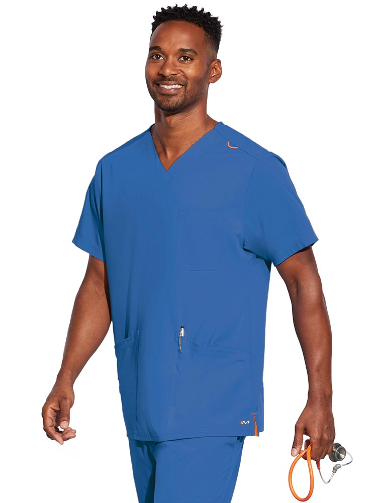A young male CNA wearing a Barco Motion Unisex V-Neck Scrub Top in Royal size Extra-Large featuring a V-neckline with lap over styling.