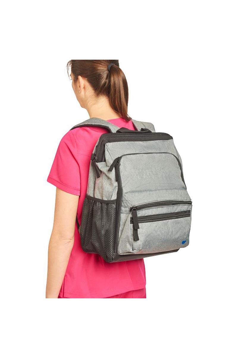 A young female Registered Nurse wearing a Nurse Mates Ultimate Backpack in "Grey Linen" featuring a variety of pockets & compartments to fit everything from laptops, medical supplies & more.