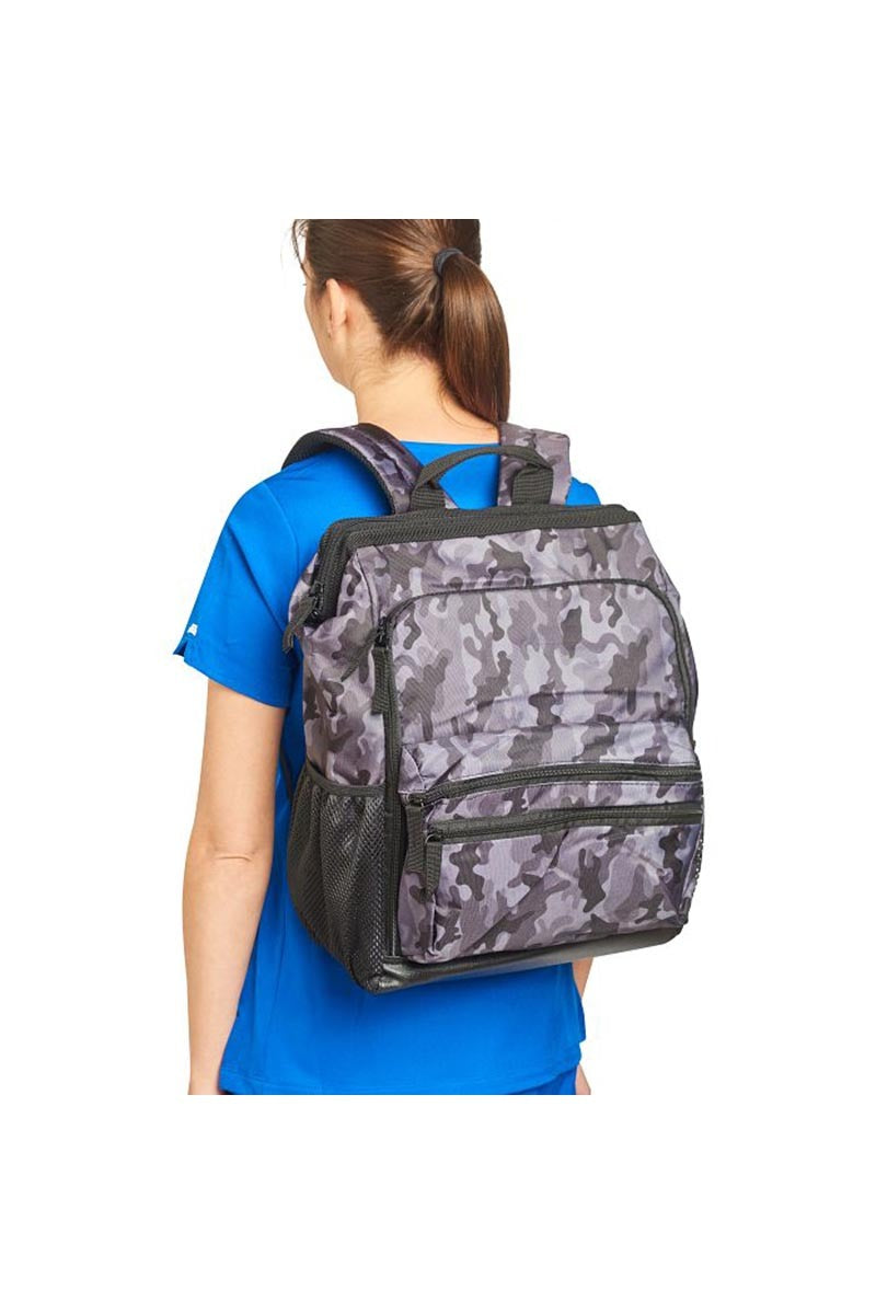 A young female Registered Nurse wearing a Nurse Mates Ultimate Backpack in "Grey Camo" featuring a variety of pockets & compartments to fit everything from laptops, medical supplies & more. 