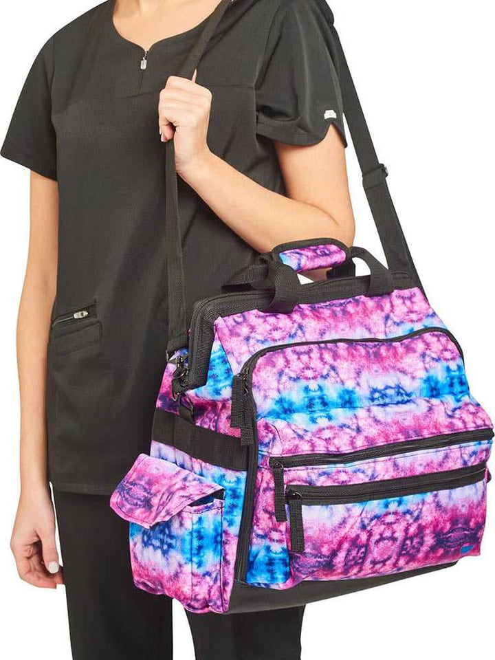 A young female Home Care Registered Nurse carrying a Nurse Mates Ultimate Medical Bag in "Berry Blue Tie Dye" featuring an adjustable nylon strap.