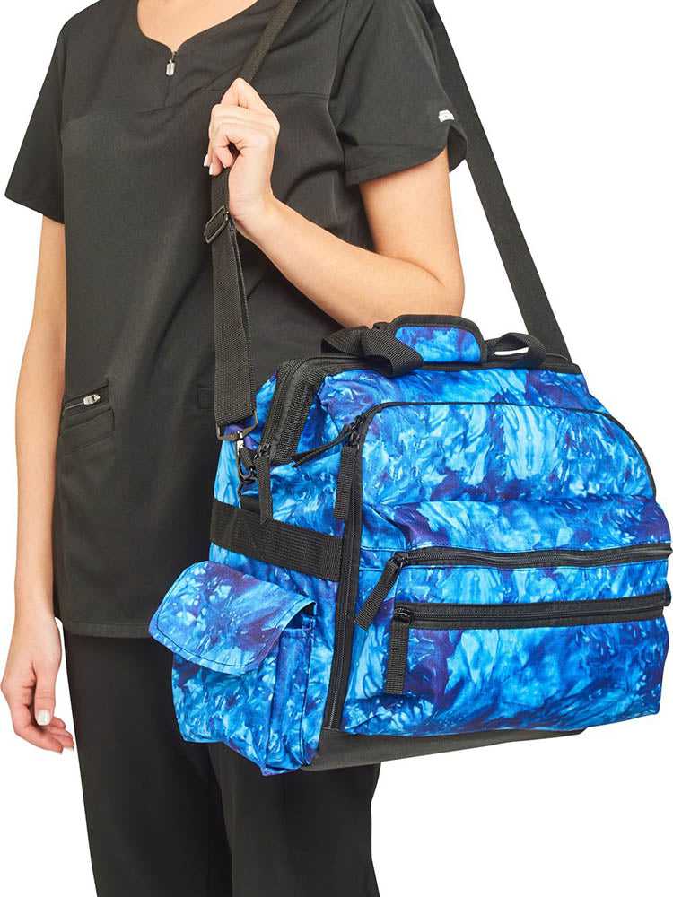 A young female RN carrying a Nurse Mates Ultimate Medical Bag in "Blue Crystals Tie Dye" featuring an adjustable nylon strap.