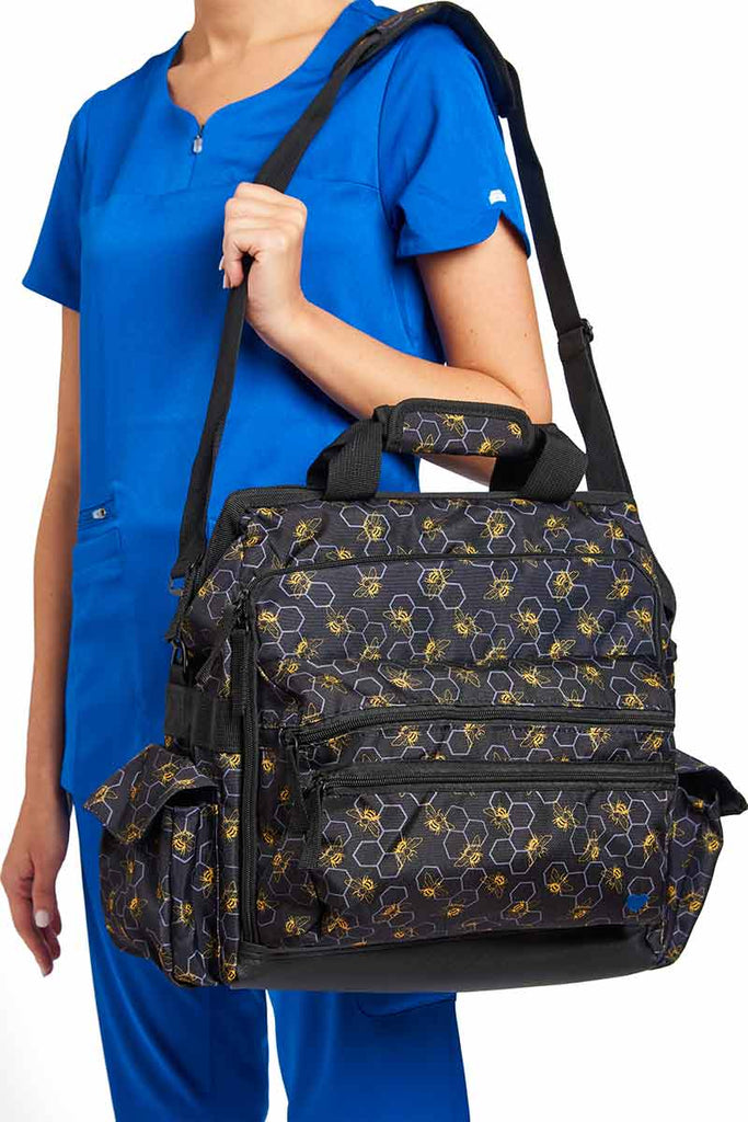 A young female RN carrying a Nurse Mates Ultimate Medical Bag in "Busy Bees" featuring an adjustable nylon strap.