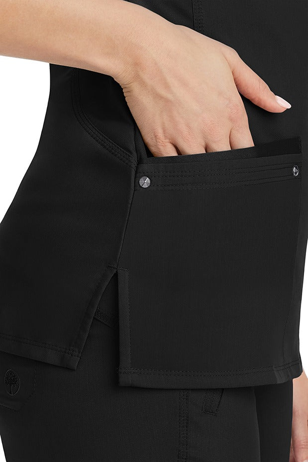 A young woman wearing a Women's Juliet Yoga Scrub Top from Purple Label by Healing Hands in Black featuring side slits for additional range of motion.